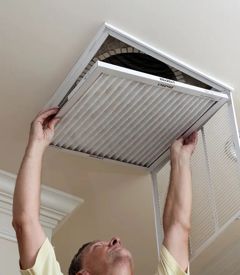 Senior Male Reaching Up to Open Filter Holder for Air Conditioning Filter in Ceiling